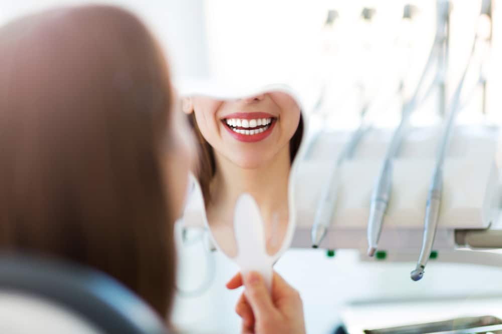 woman looking at smile after periodontist treatment